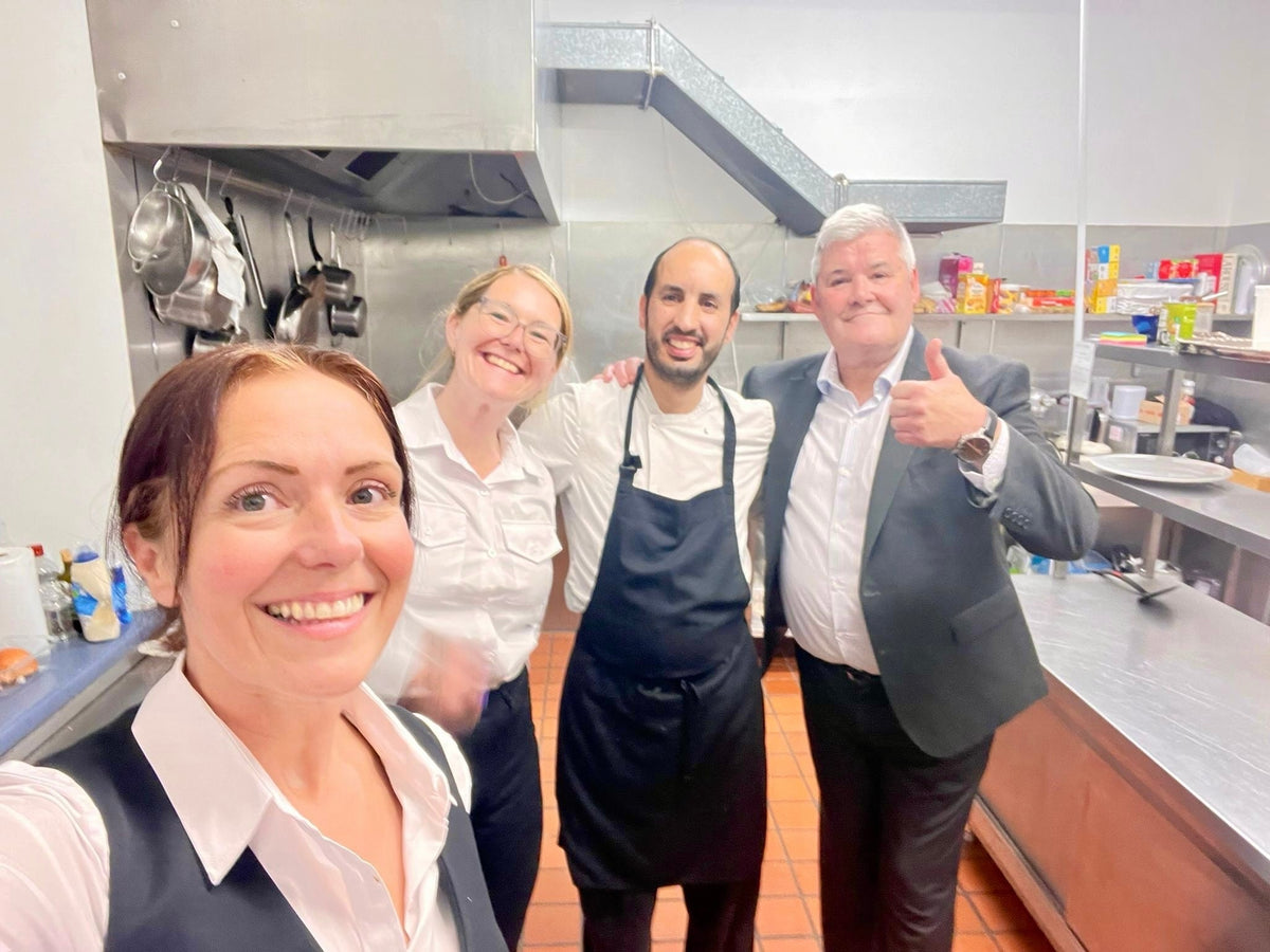 Chef Anas with the two front-of-house team members and a guest giving a thumbs up in the kitchen at Teaninich Castle near Alness, after a 50th-birthday banquet
